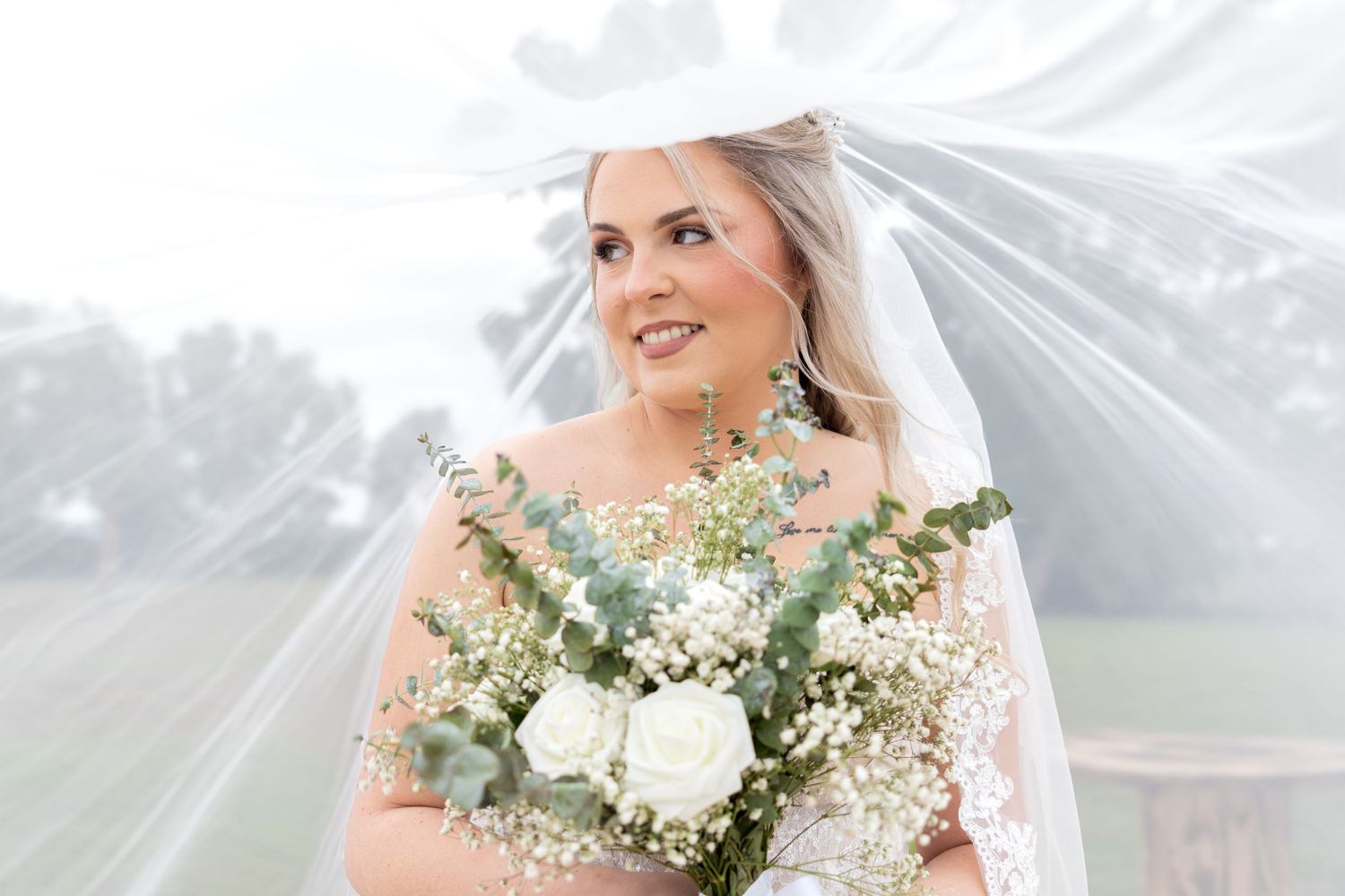 Bridal portrait with delicate white baby's breath flowers and flowing veil in soft lighting.