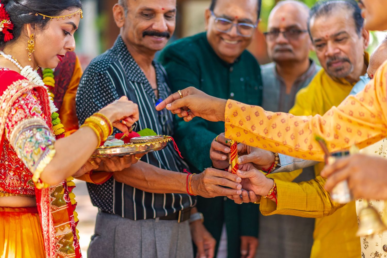 Traditional Indian wedding ceremony with bride in red saree and guests exchanging ritual offerings.