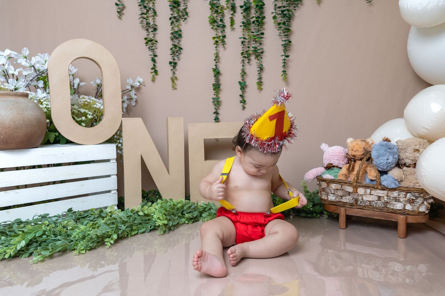Baby in party hat celebrating first birthday with ONE letter decorations.