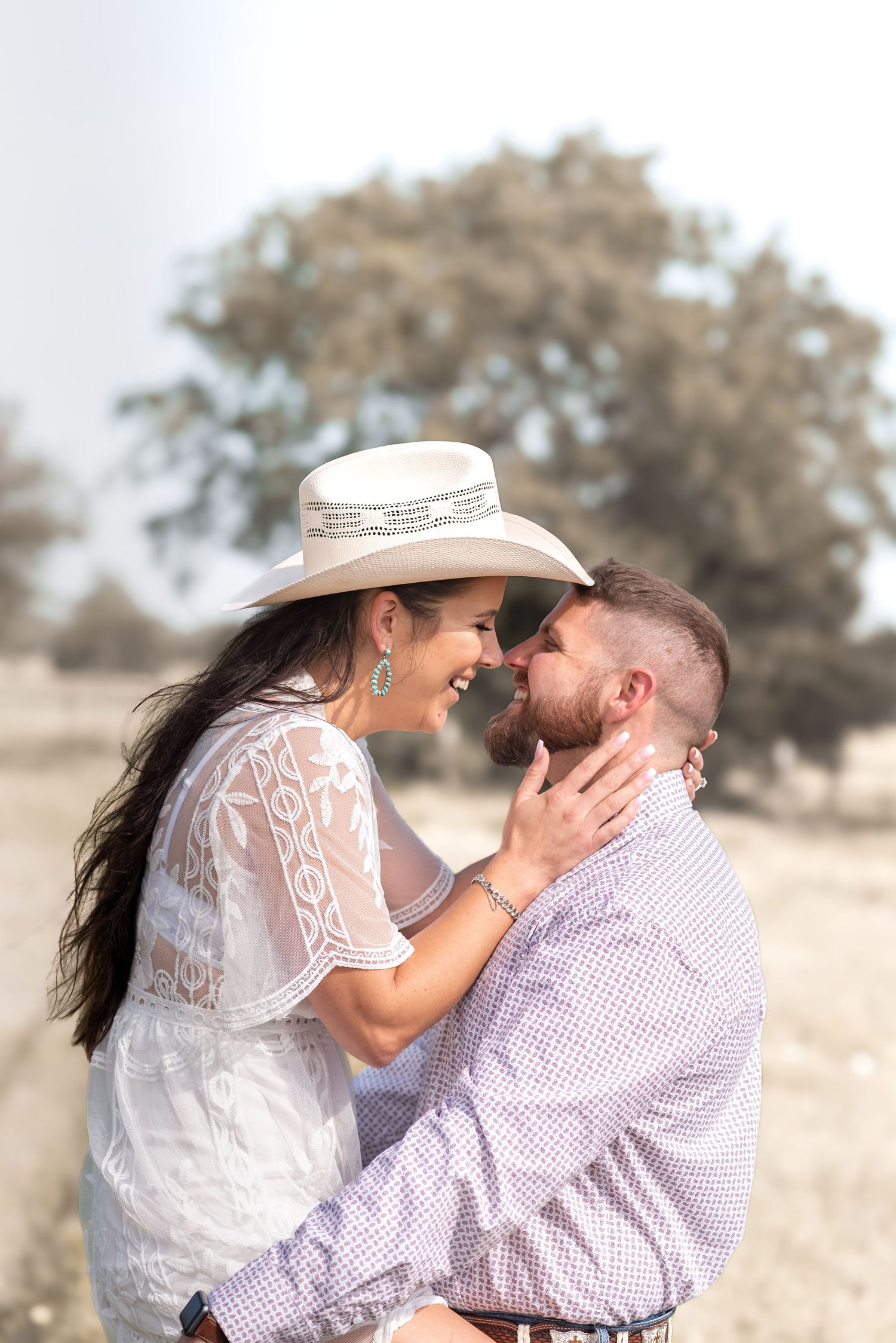 Romantic couple in western attire sharing an intimate moment outdoors.
