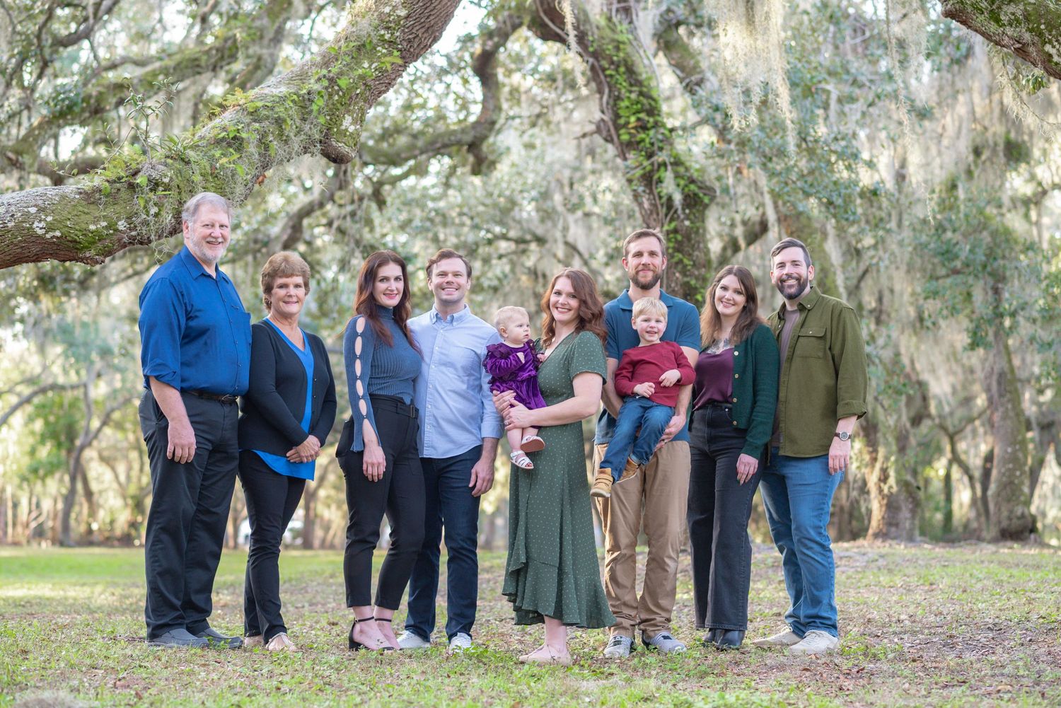Extended family portrait under Spanish moss-draped oak trees outdoors.