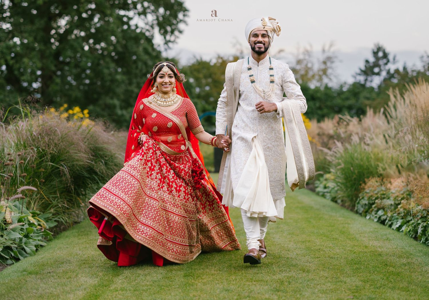 Akshay and Sherali Sikh wedding – bride and groom walking hand in hand outdoors, bride in red lehenga, groom in white sherwani, Sikh wedding