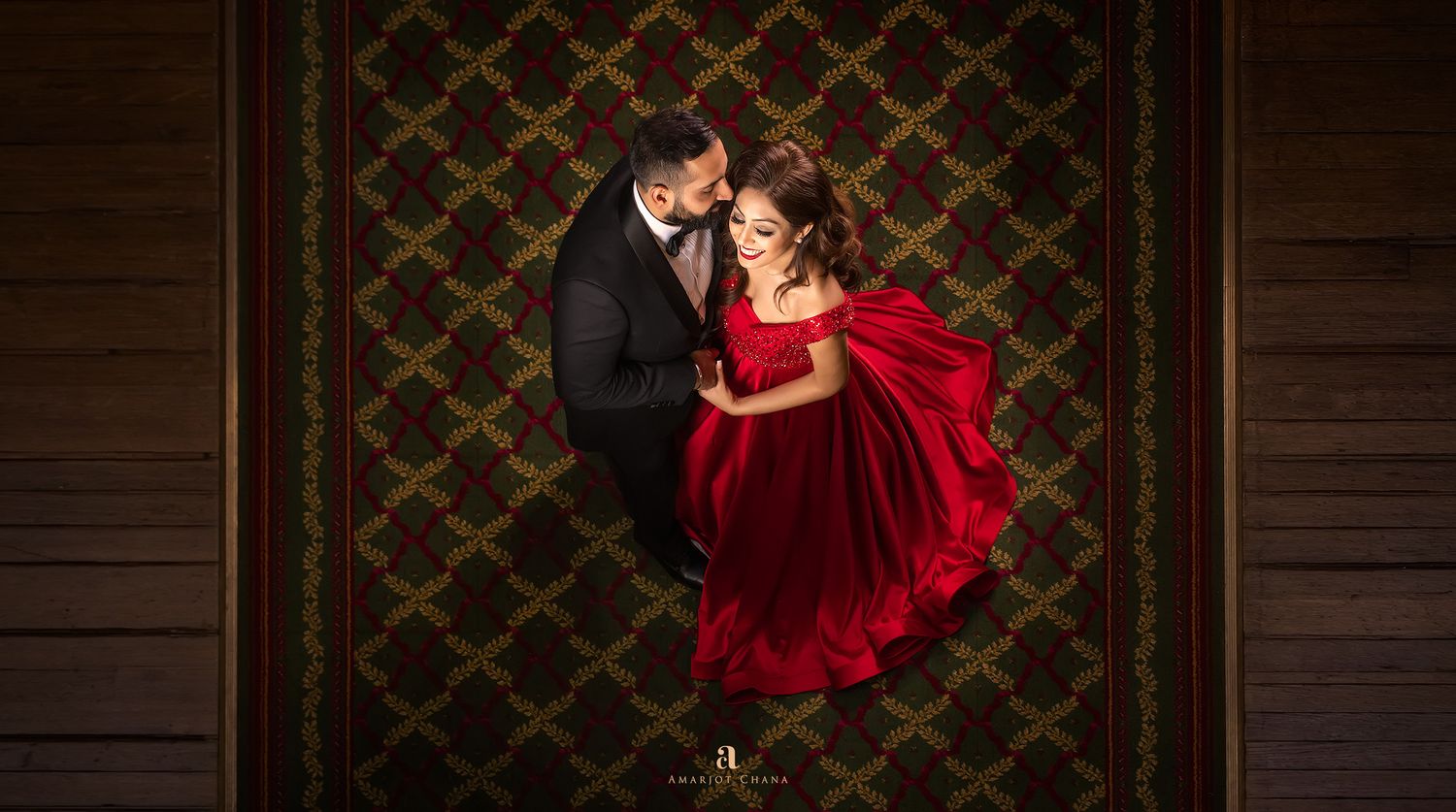 Pre-wedding portraits – aerial view of couple dancing, woman in flowing red ball gown on ornate carpet, editorial Indian wedding photography