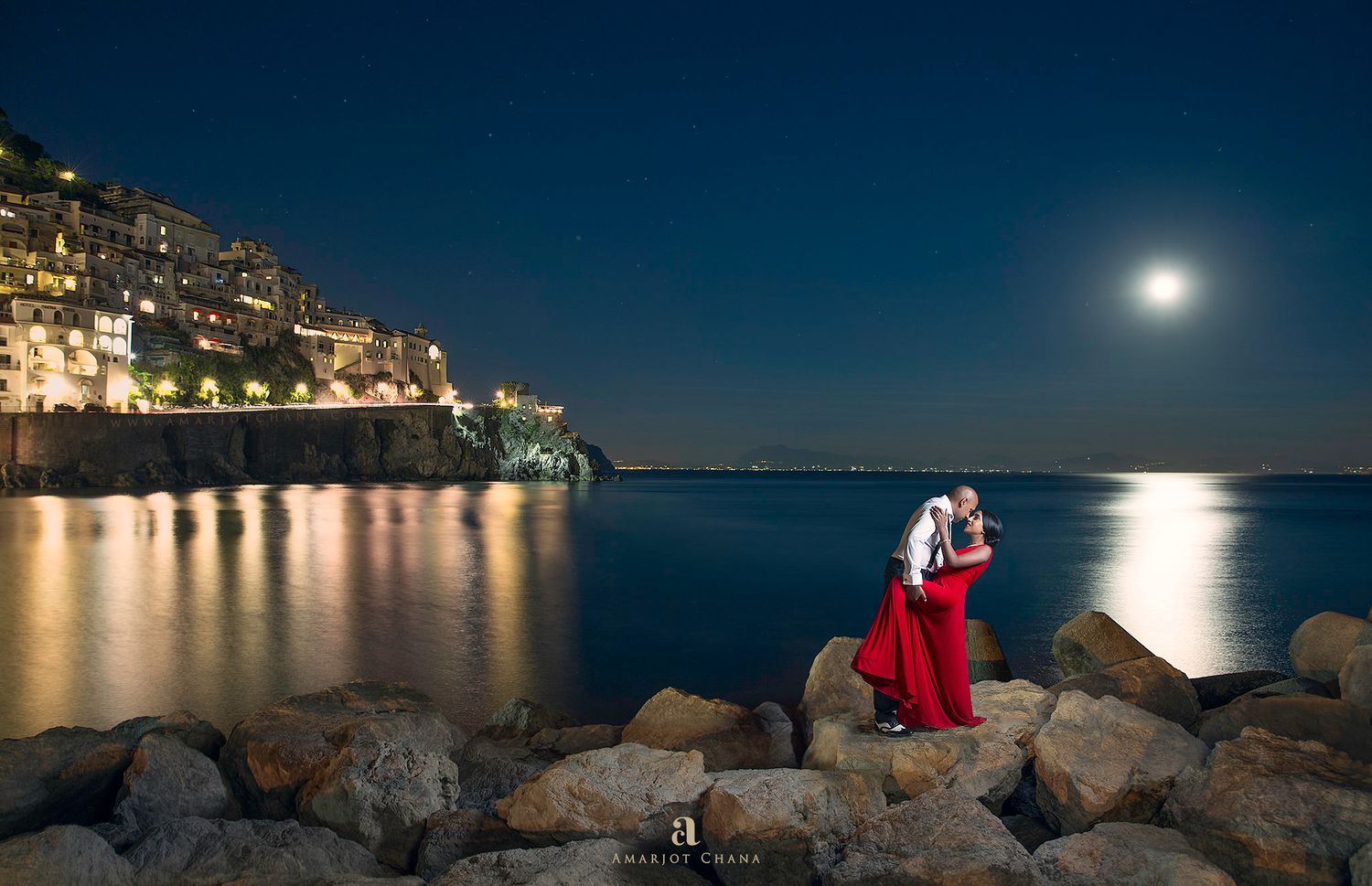 Robin and Jyoti pre-wedding portraits – couple in red and white attire on coastal rocks under full moon at night, dramatic Indian wedding ph