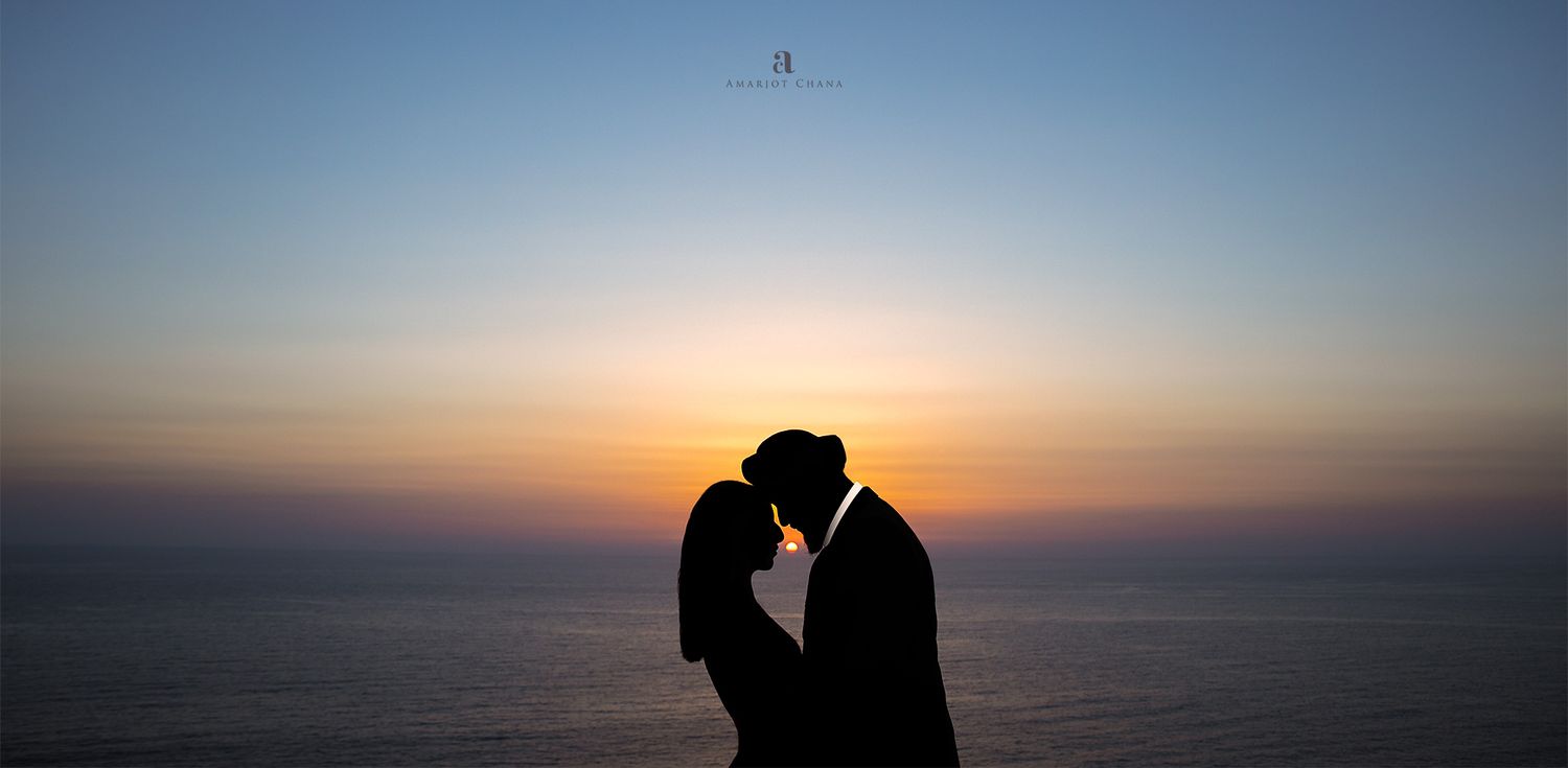 Pre-wedding portraits – romantic couple silhouette kissing against vibrant blue and orange ocean sunset, Indian wedding photo