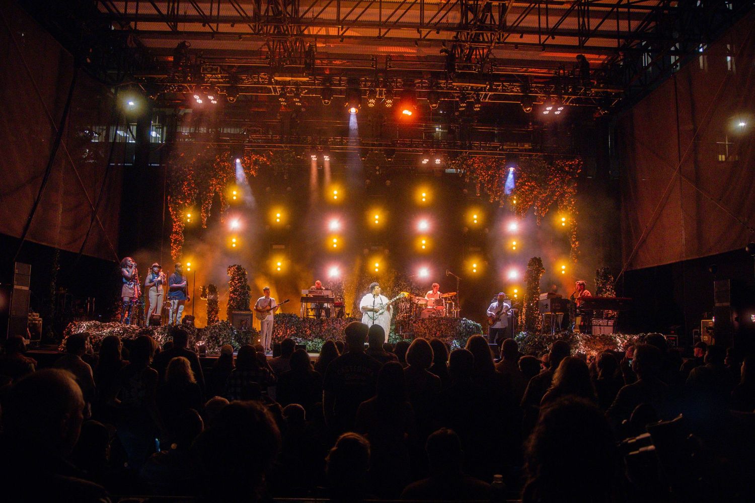 Concert venue filled with crowd watching illuminated stage with warm lighting effects.