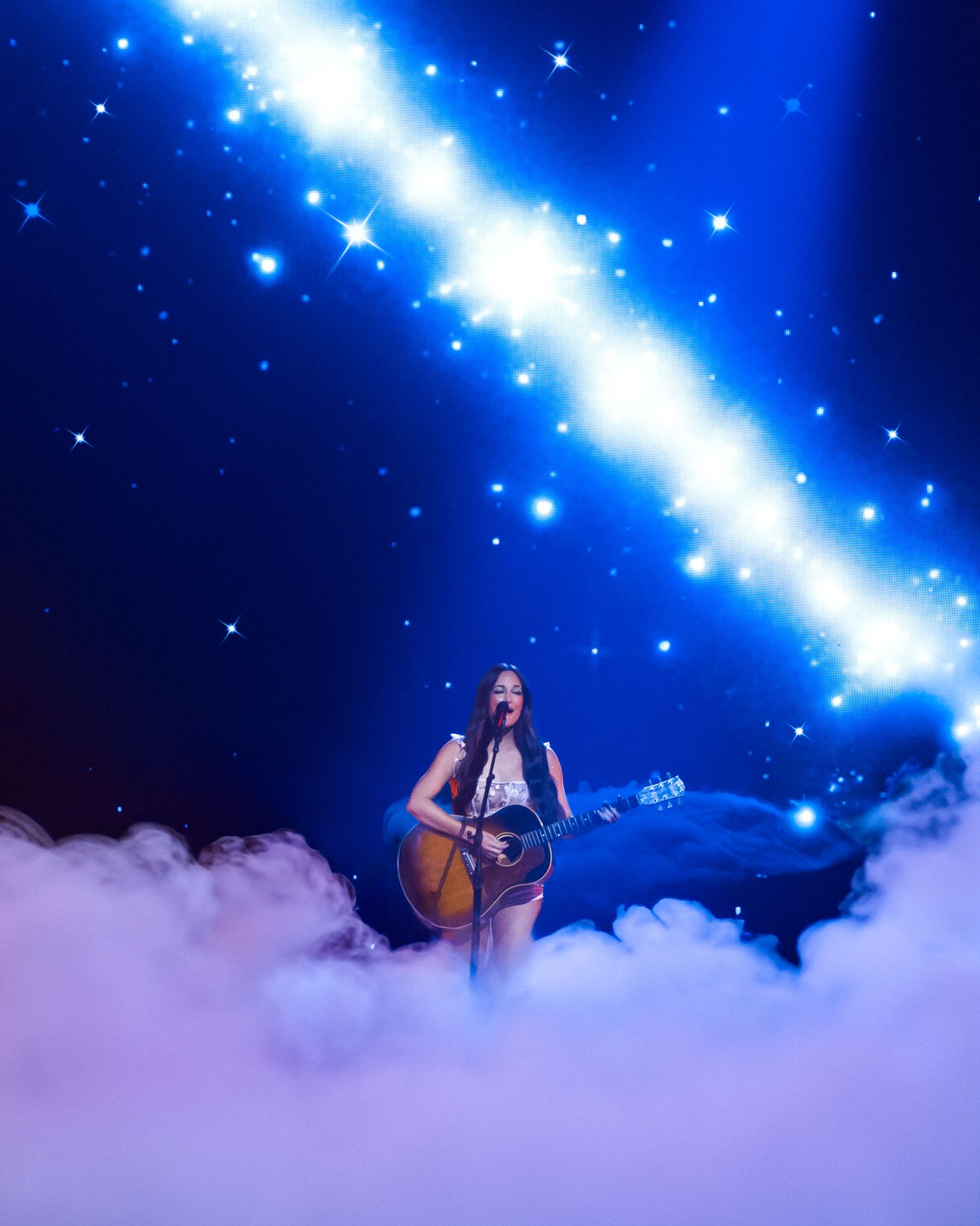 Concert stage performance with dramatic blue lighting and fog effects creating a dreamy atmosphere.