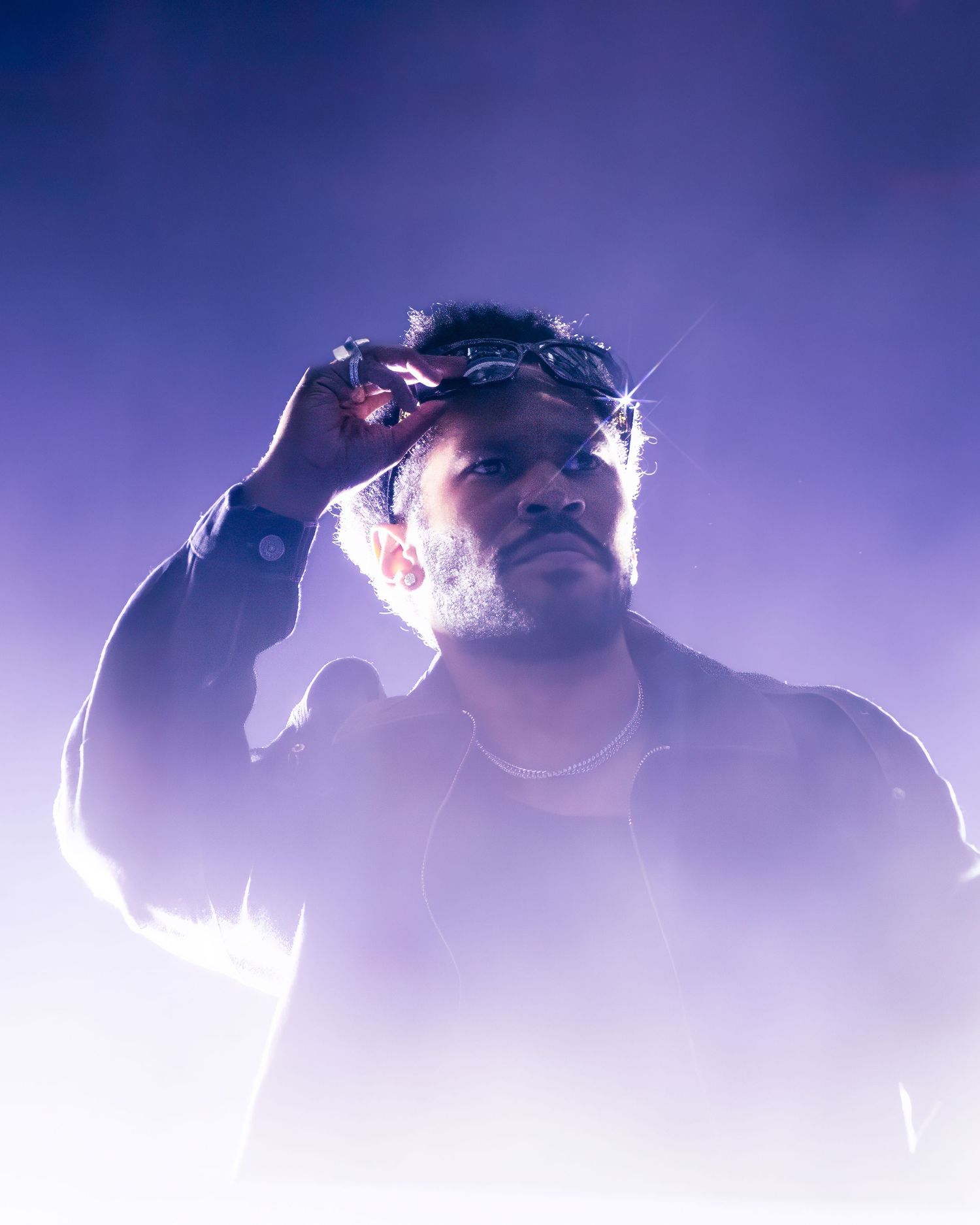 Backlit performers in fog creating dramatic silhouettes against purple lighting.