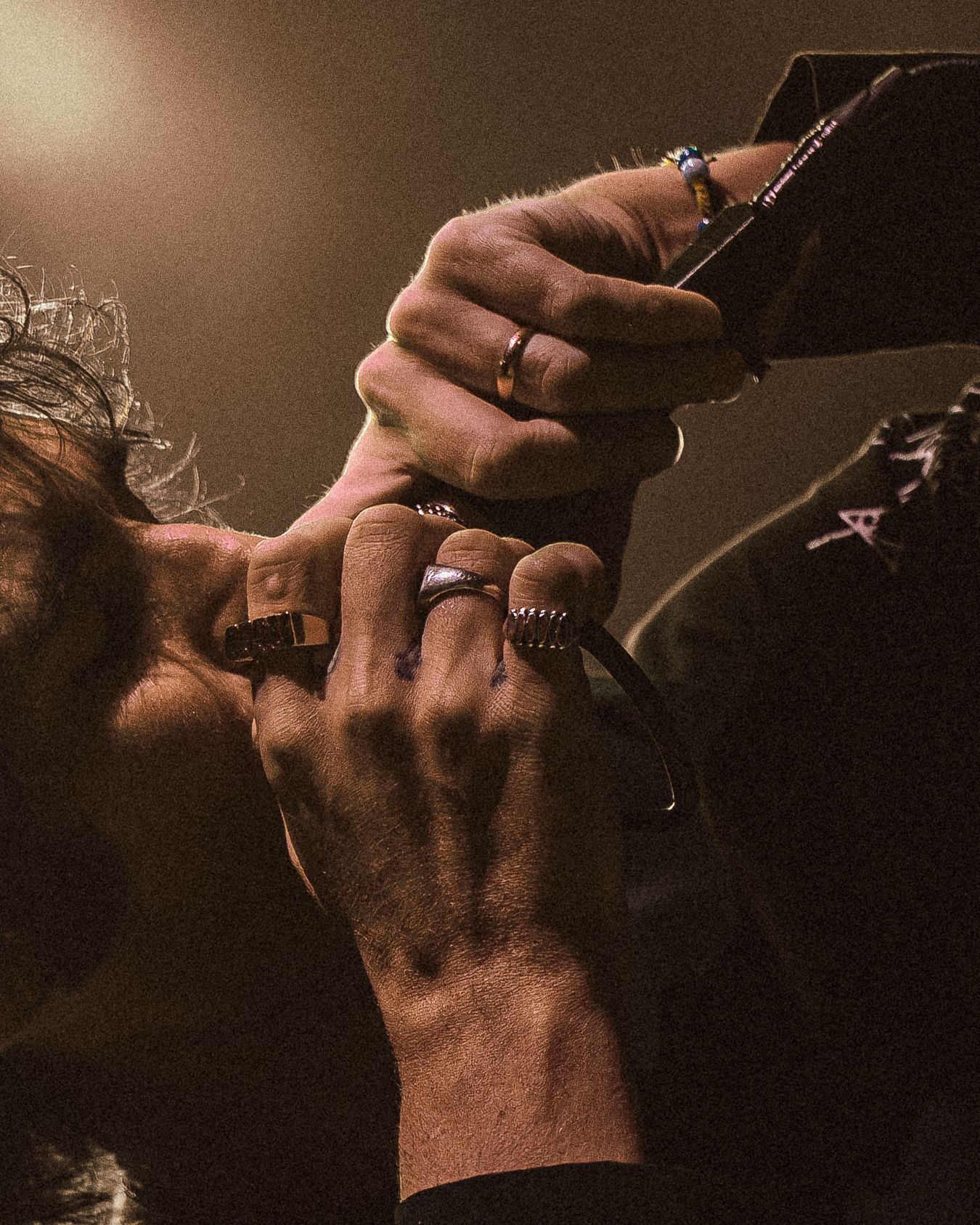 Dramatic low-angle concert shot with warm lighting and silhouetted performer on stage.