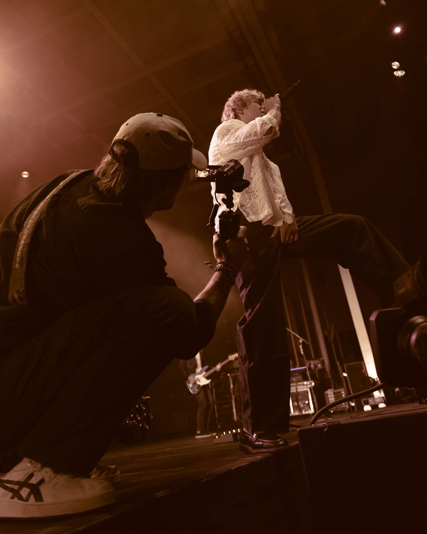 Concert performers silhouetted in dramatic sepia lighting on stage during a live show.