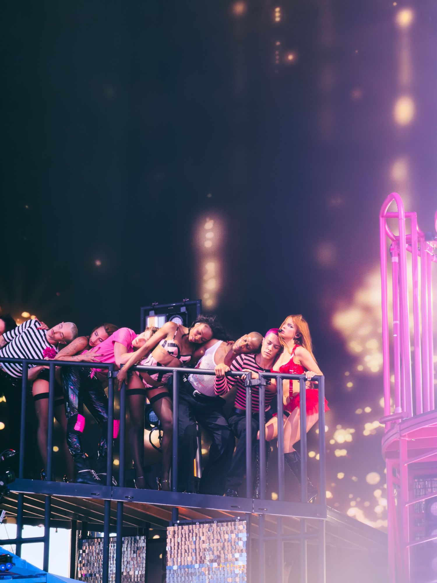 Group of people on a raised platform at a vibrant concert venue with glowing bokeh lights in the background.