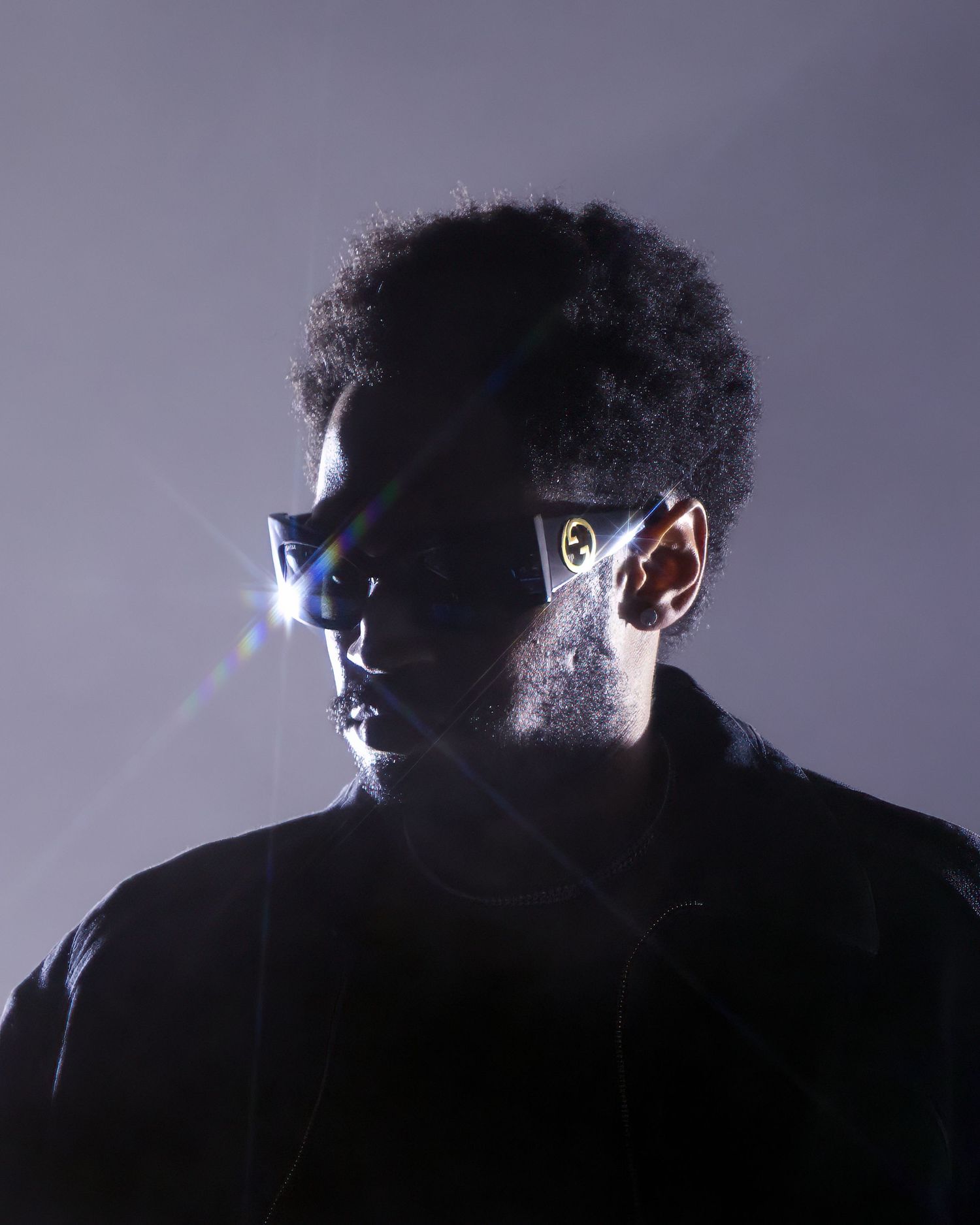 Dramatic side-lit silhouette profile against purple background creates mysterious atmosphere.