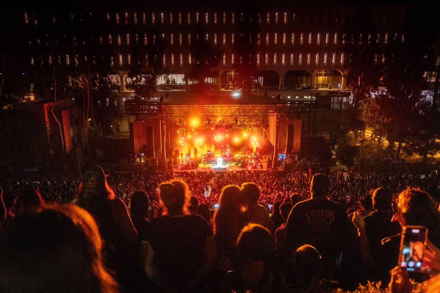 Concert stage illuminated with vibrant red and orange lights creating a dramatic atmosphere during a live performance.