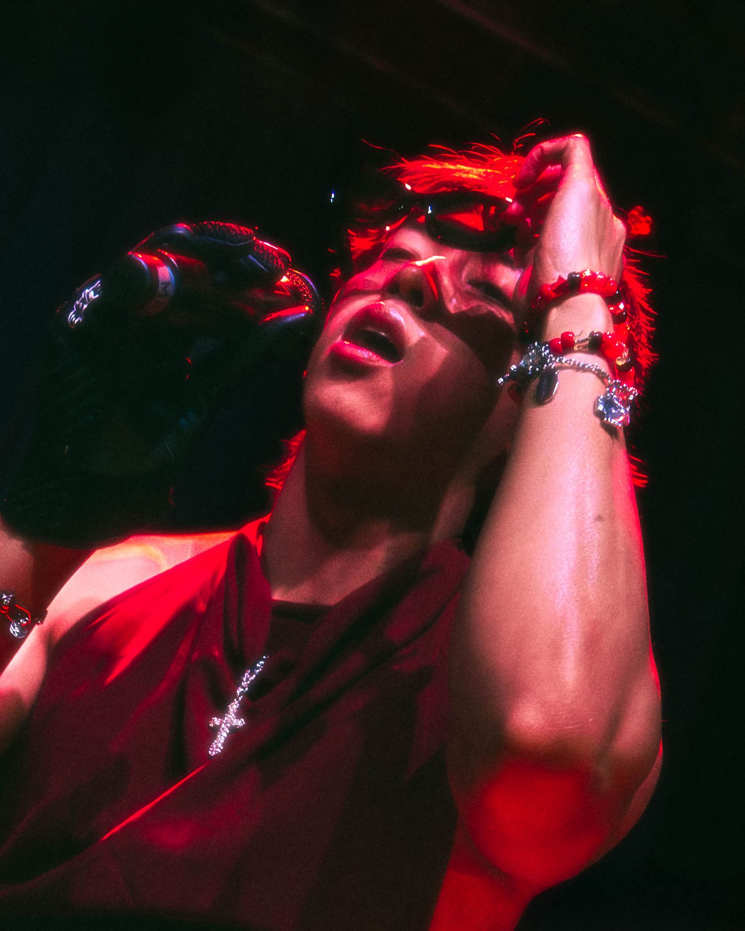 Concert performance captured in dramatic red lighting with intense stage effects.