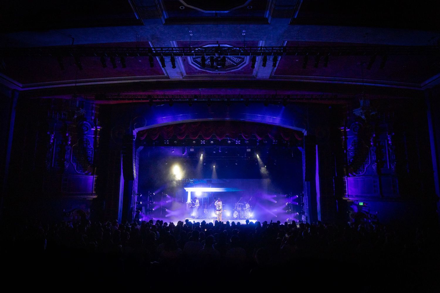 Wide concert venue shot with blue stage lighting illuminating the distant performance space.