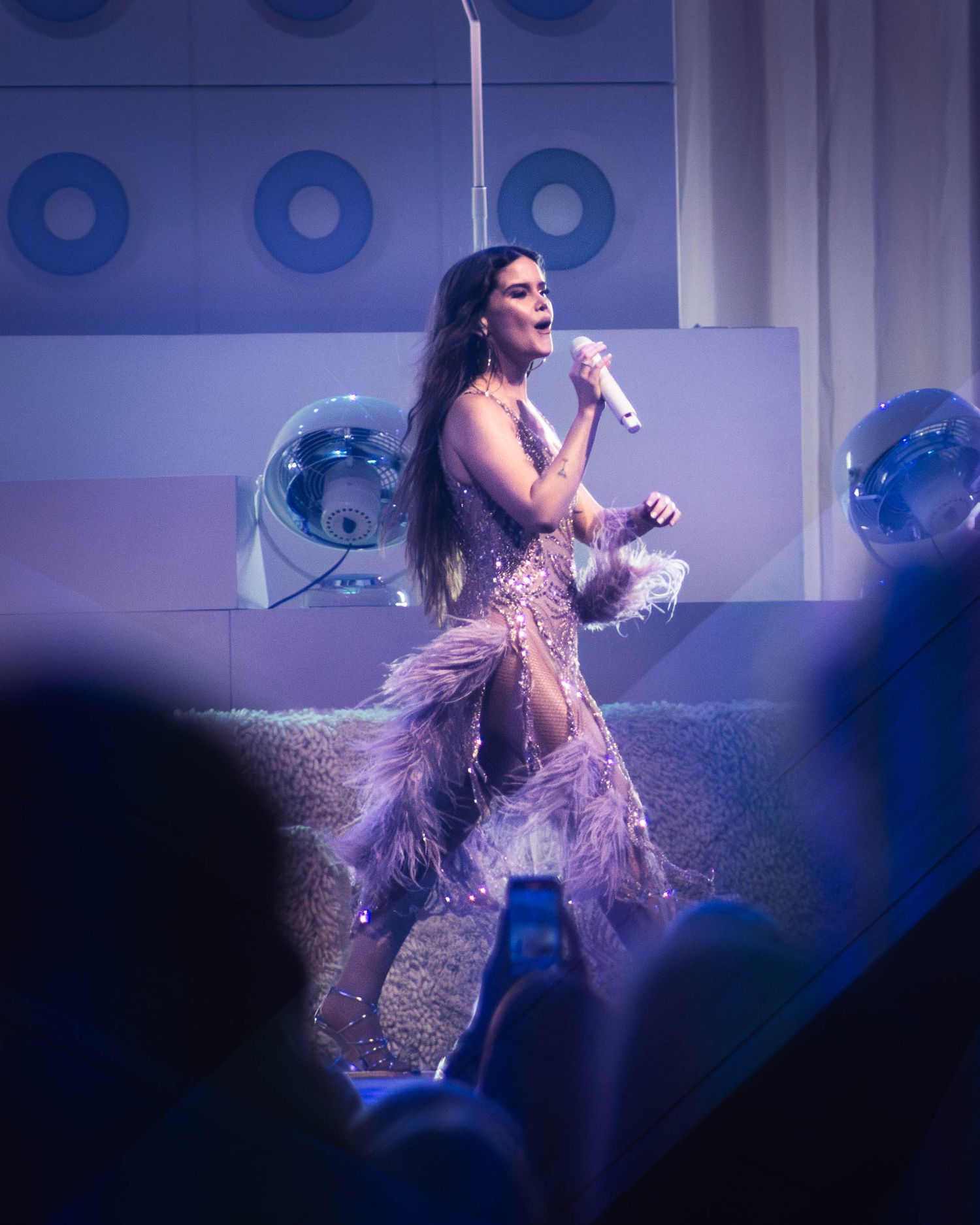 Performer in a sparkly outfit dancing on stage with dramatic lighting effects.