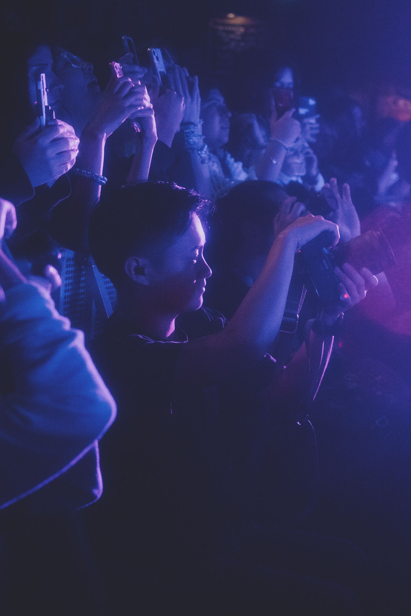 Concert crowd silhouettes illuminated by blue stage lighting during live performance.