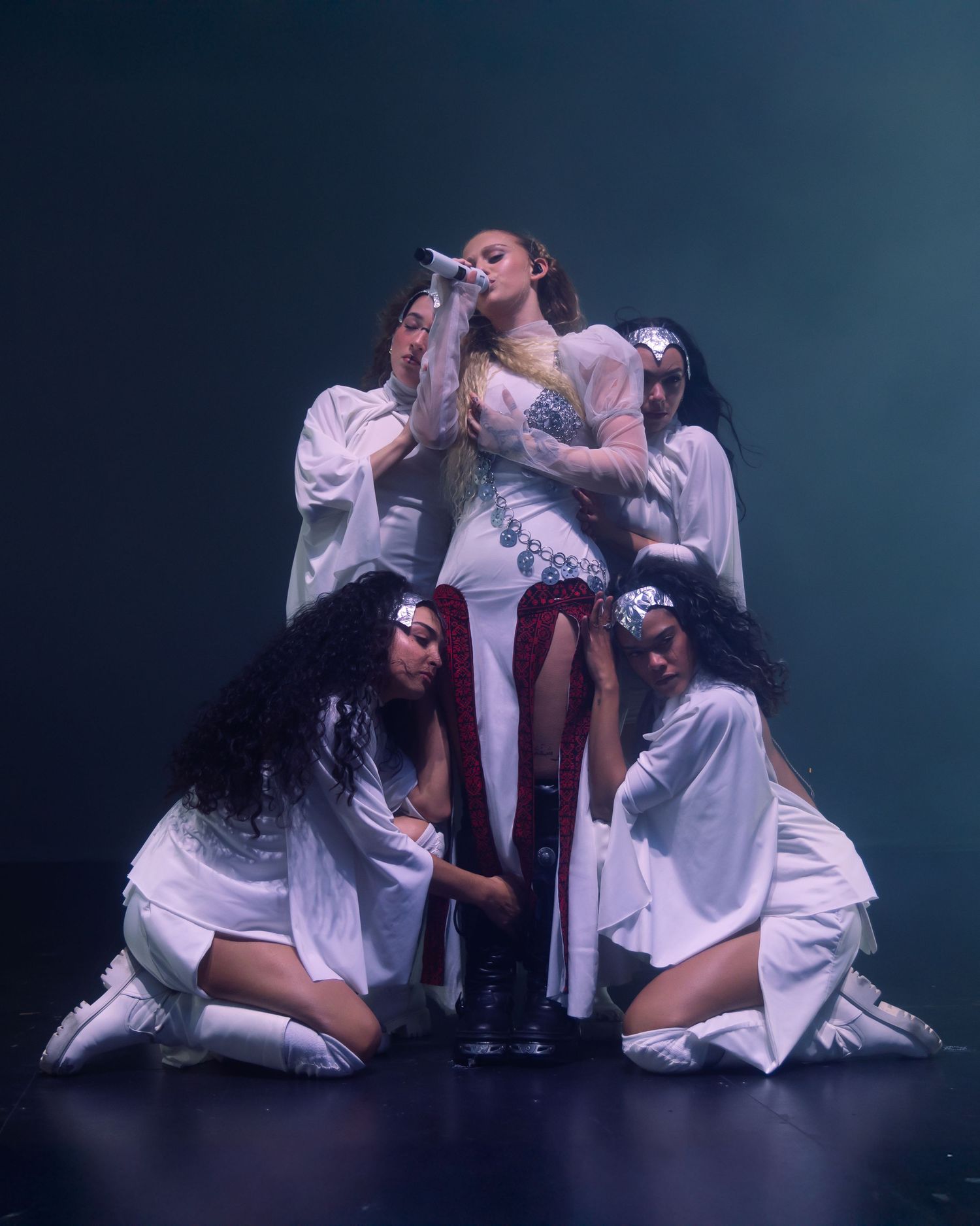Artistic dance performance with performers in white outfits creating dramatic group pose.