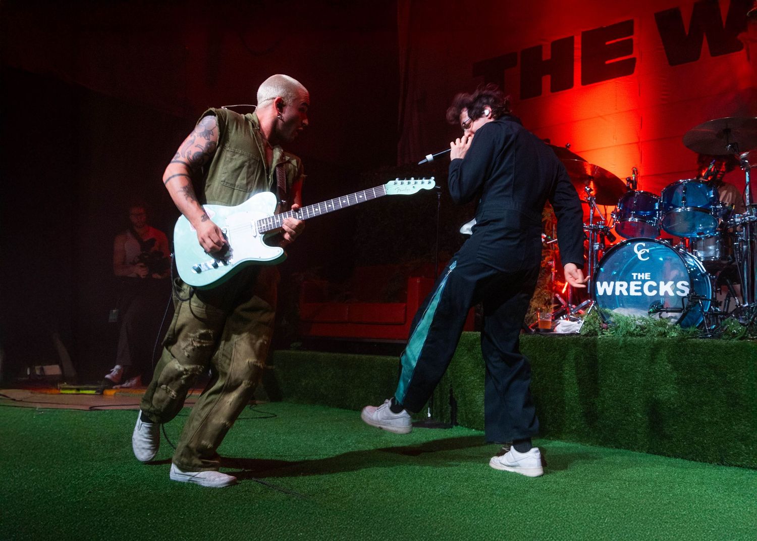 Two musicians performing on stage with red lighting and The Beaches band logo visible.