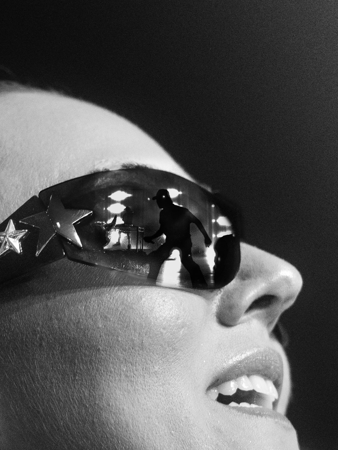 Black and white artistic photo showing sunglasses reflecting light in a dramatic close-up composition.