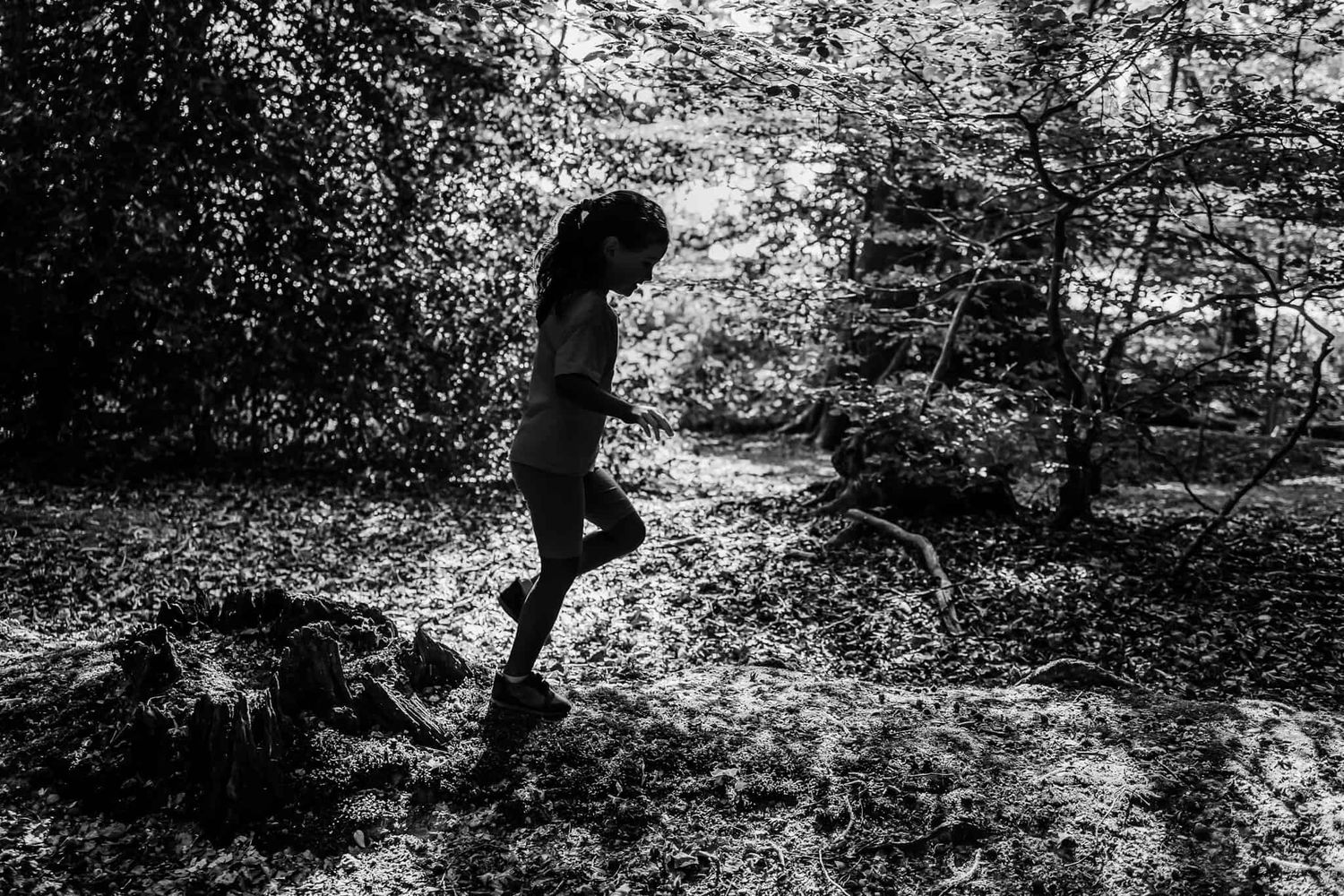 A black and white image of a girl's silhouette as she explores the woodland.