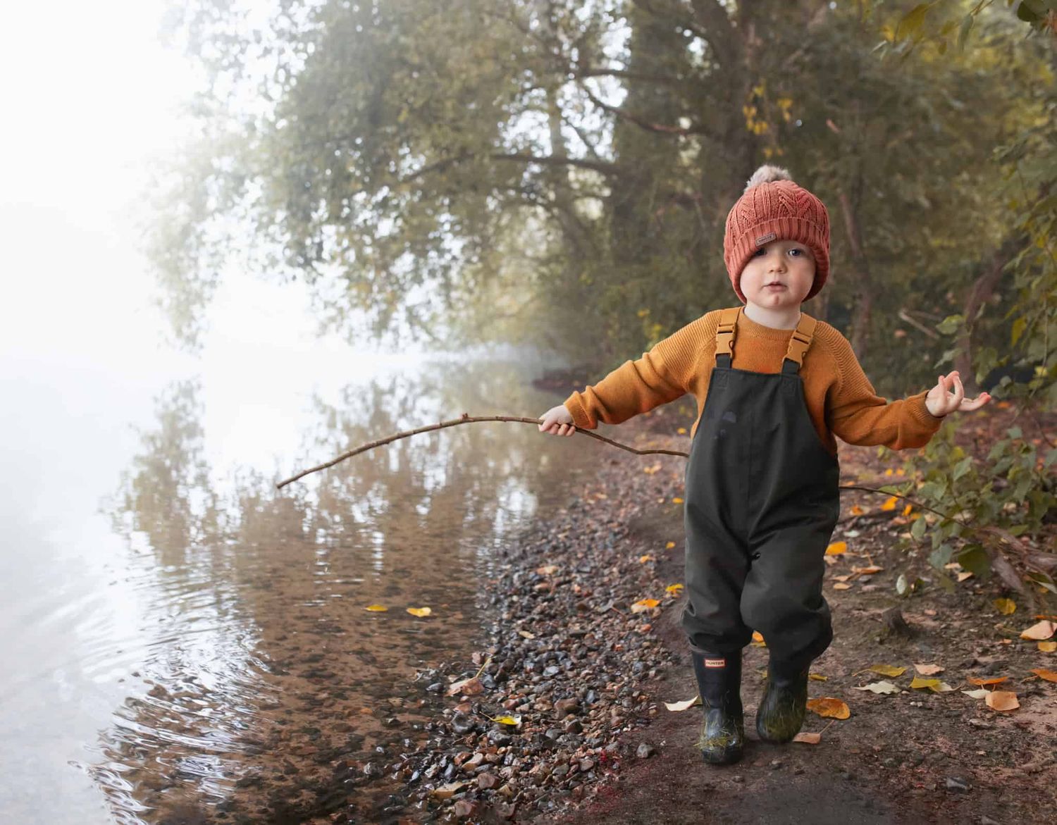 A child walking along the river on a misty morning in autumn.