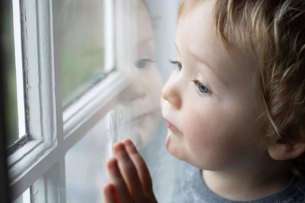 A young boy looks out of a window.
