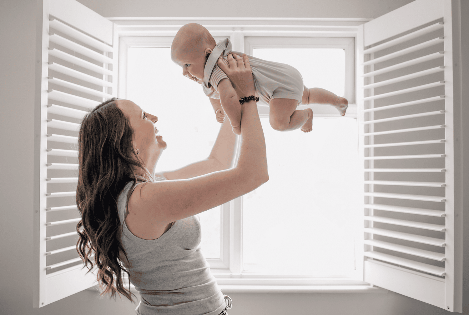 A mum throws her older baby up into the air during a photo session with her two children, held to document her maternity leave.