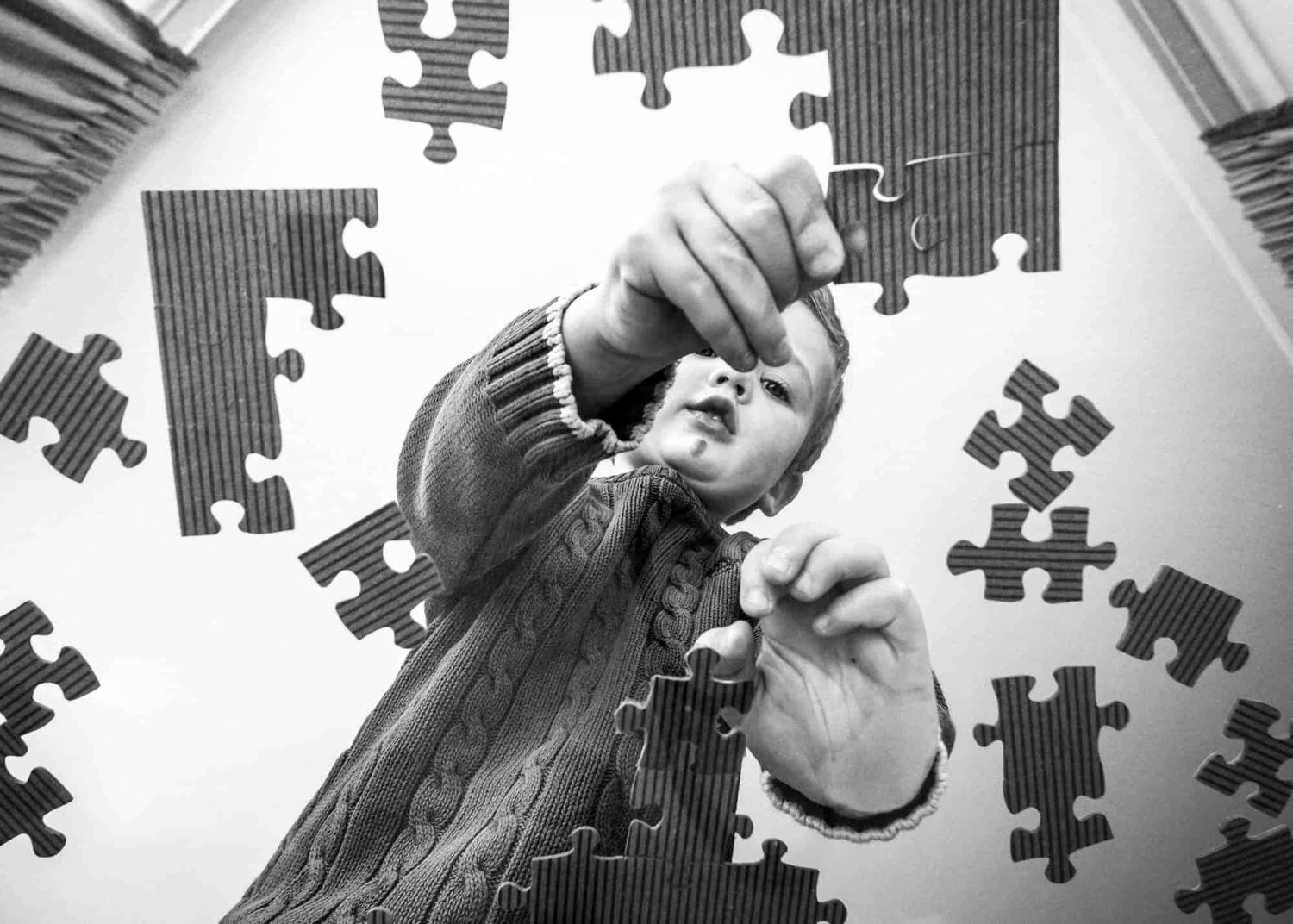A young boy putting a jigsaw puzzle together.