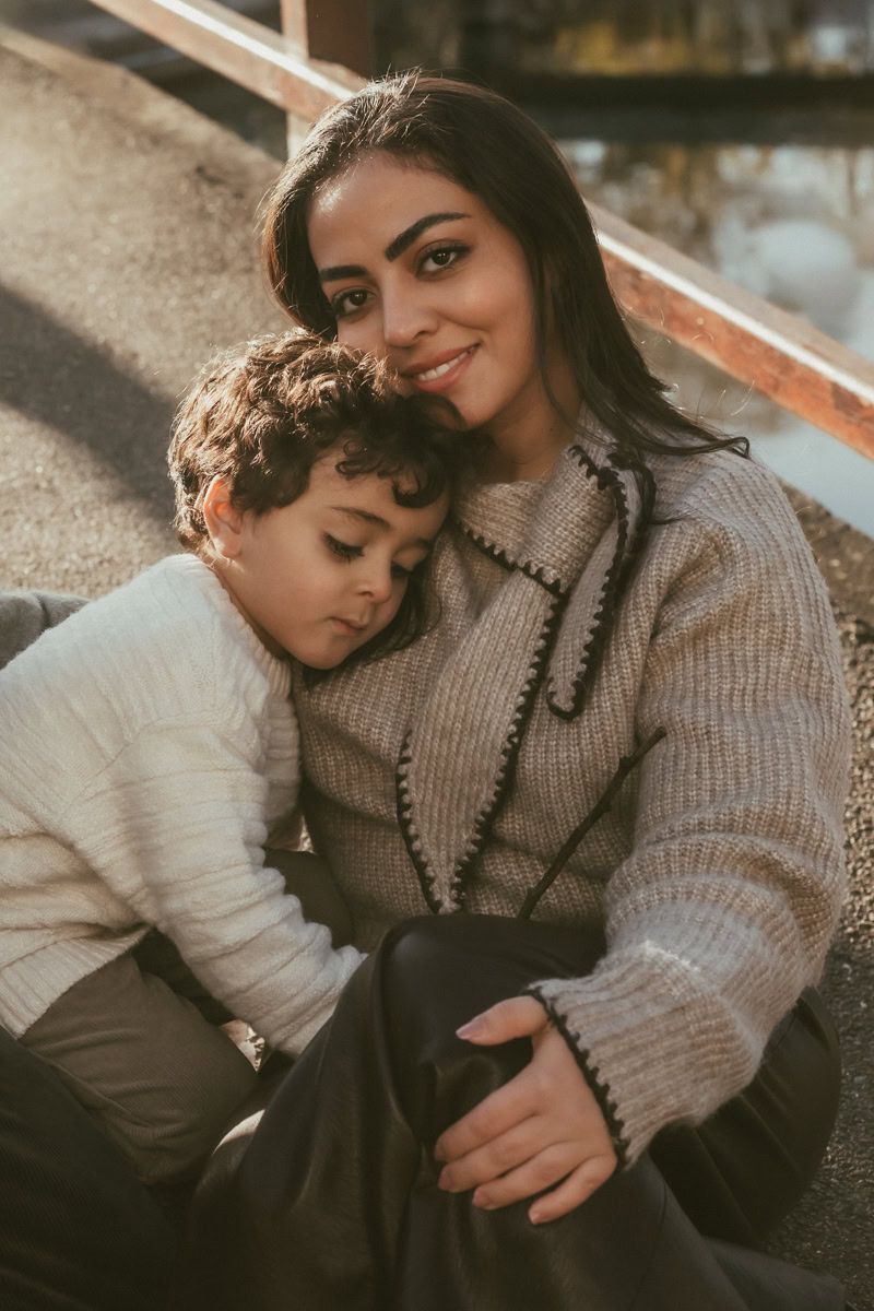 A mother and son sit together on the bridge at Marlow Lock.  He rests his head on her shoulder- a natural moment of connection.