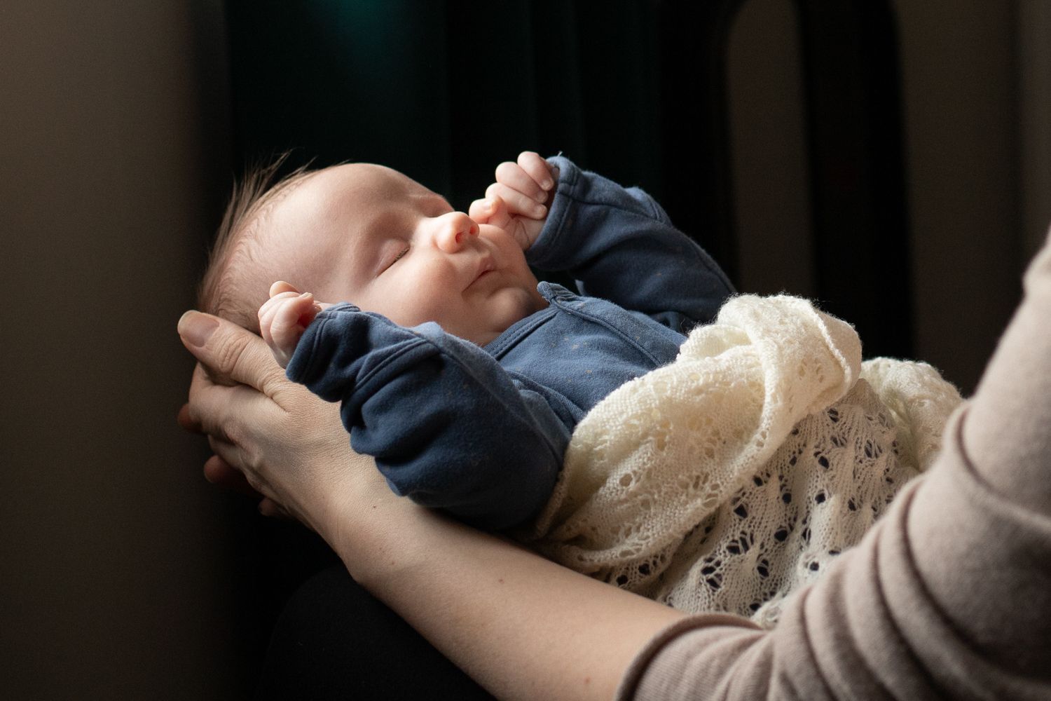 A mother cradles her month old baby in her arms.
