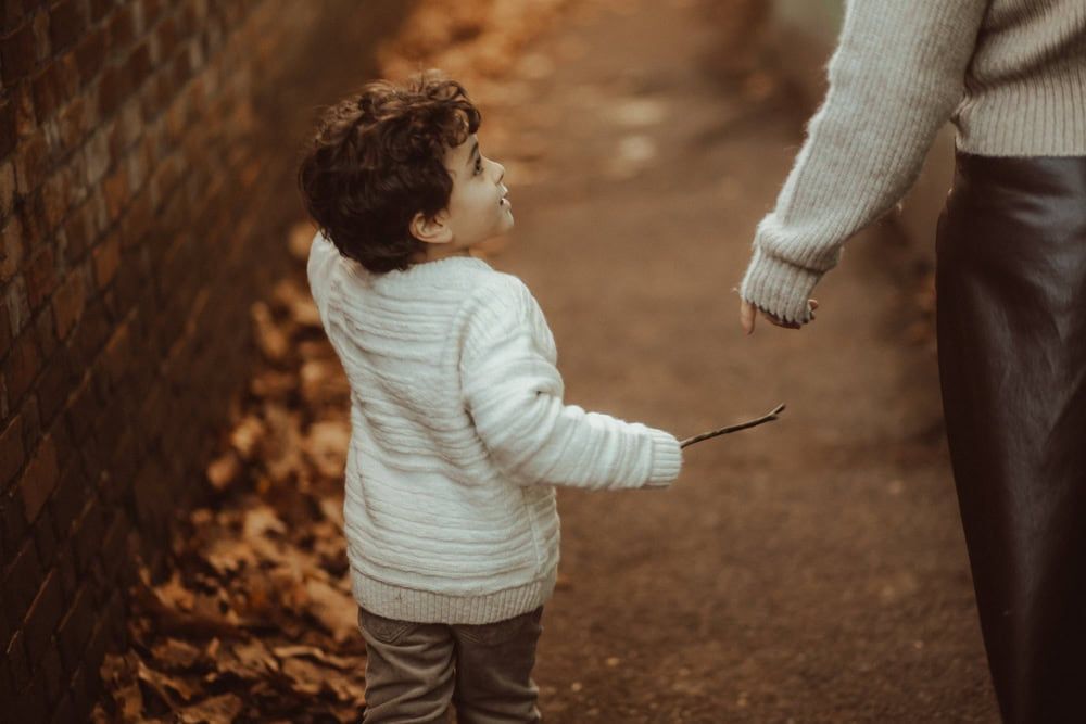 A young boy looks up towards his mother as they walk through Marlow's alleyways.