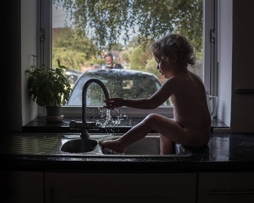 A toddler taking a bath in a sink at home in Marlow.