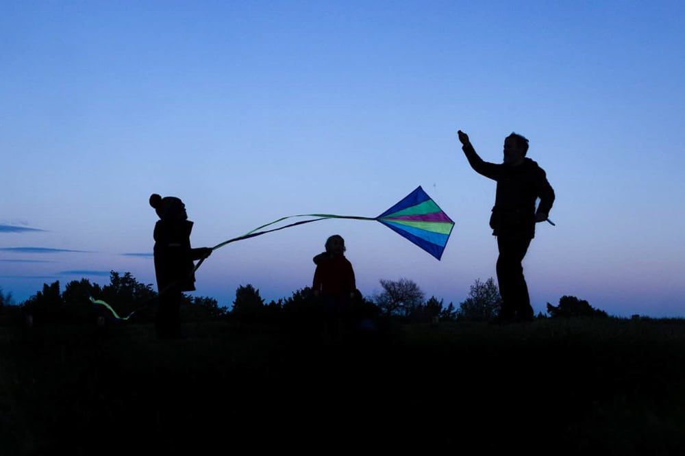 A father flying a kit with his two children on top of West Wycombe hill.