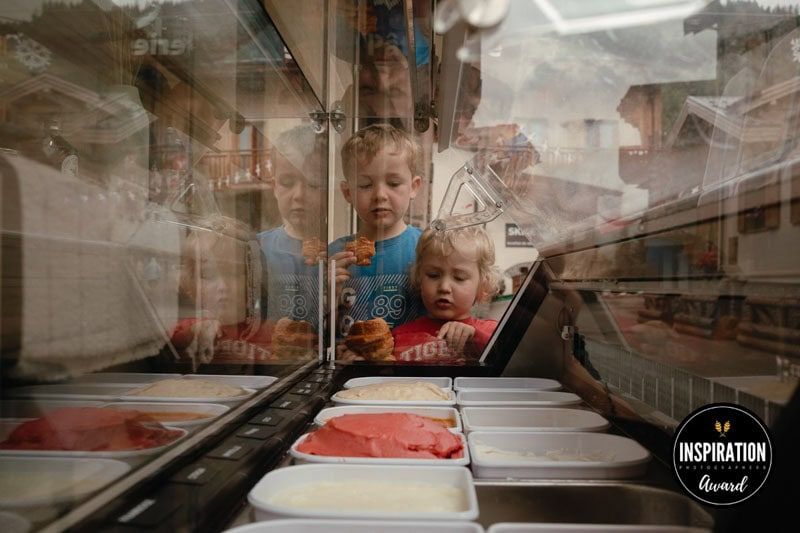 Two boys eat croissants and look into an icecream cart.