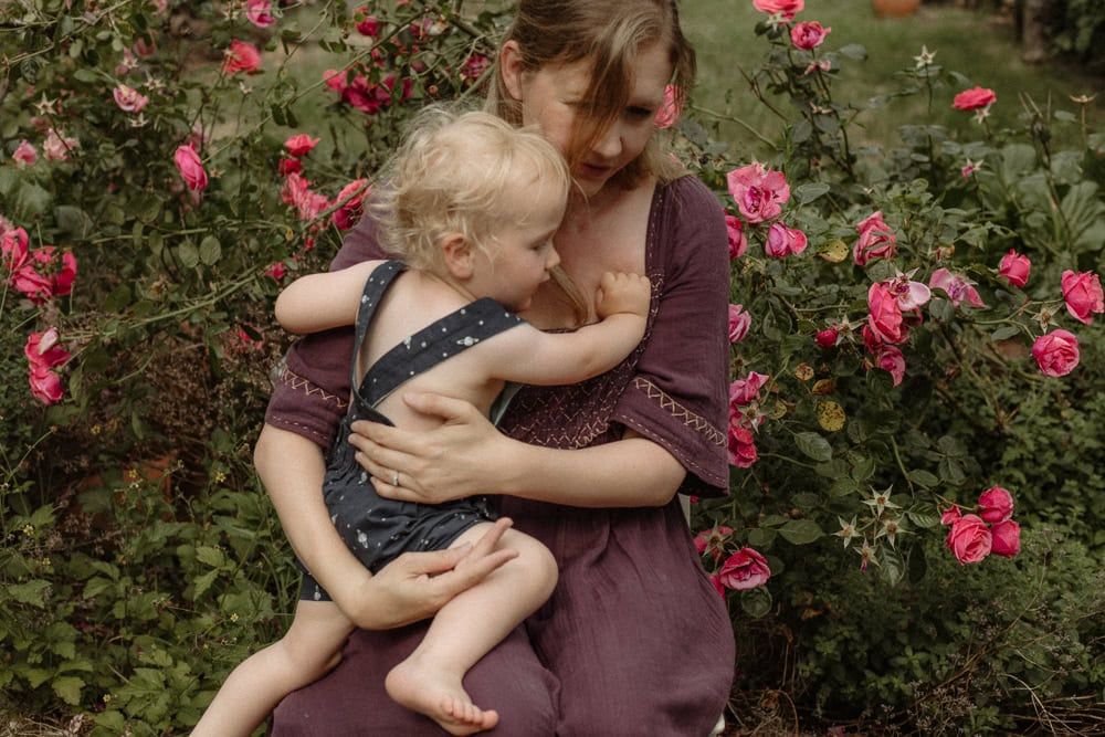 Emma holds her second son in a rose garden.
