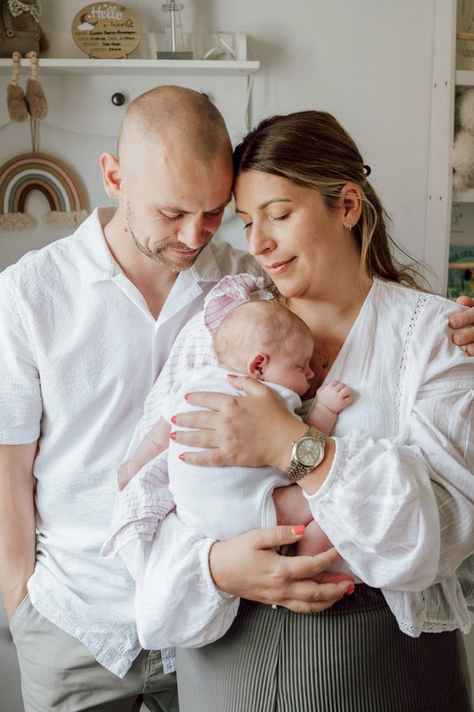 A mother and father look down at their baby, image taken in their daughter's nursery in Flackwell Heath, Buckinghamshire.