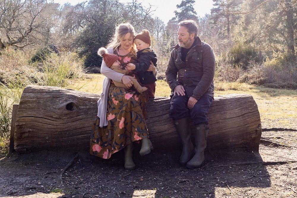 Emma with her own family, sitting on a log in Burnham Beeches not long after her second child was born.