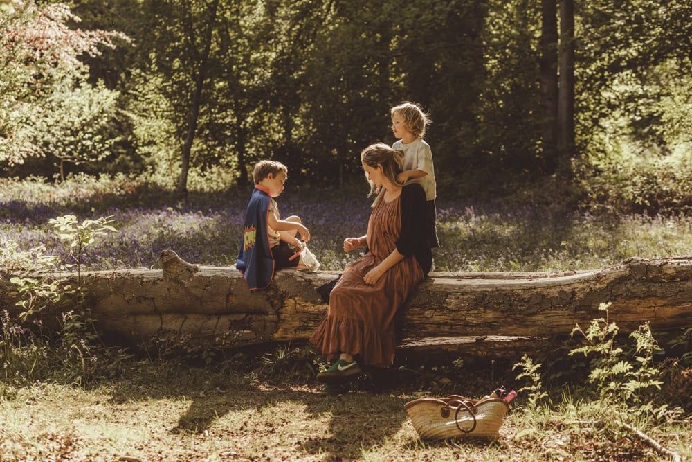 A mother has a picnic with her children on a fallen tree in Marlow Common.  Taken during a relaxed outdoor photo session.