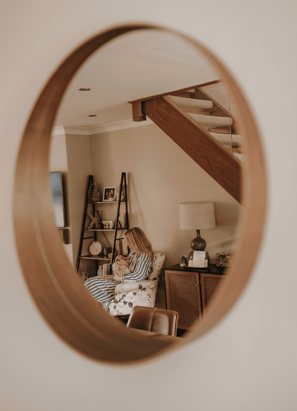 A mother feeds her newborn baby, image taken of their reflection in a mirror in their home.