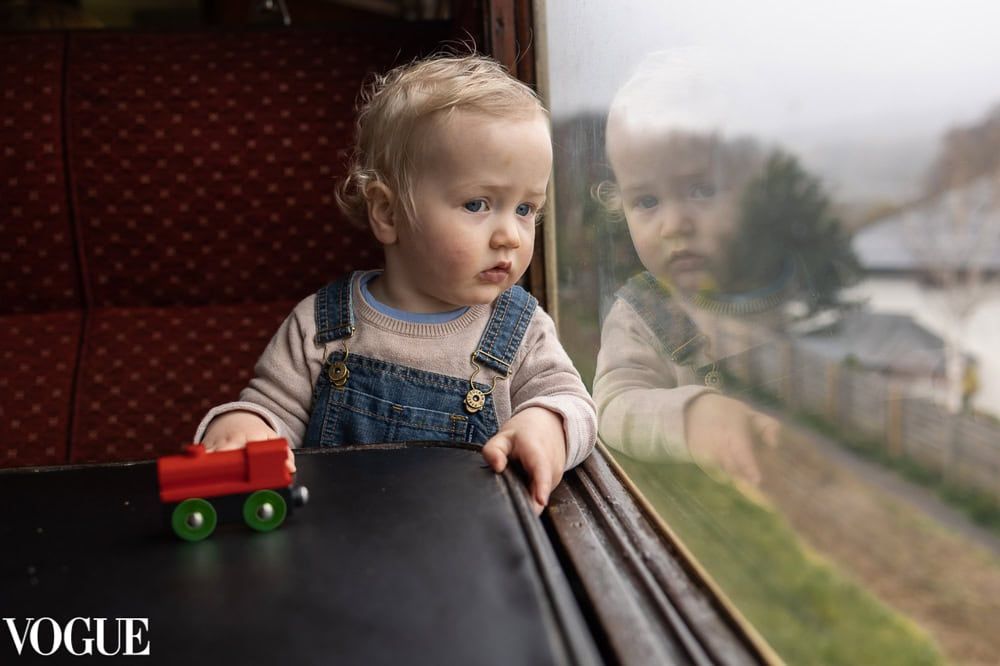 A young boy looks out of the window of a steam train.