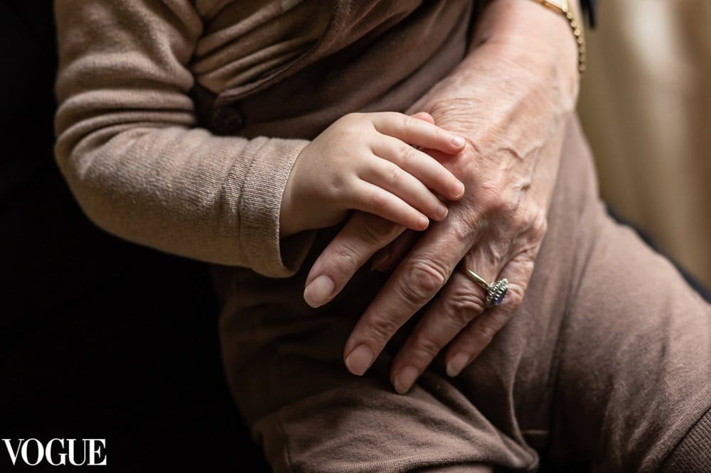 A grandmother's hand holds that of her little grandchild, showing the difference in their size and age.