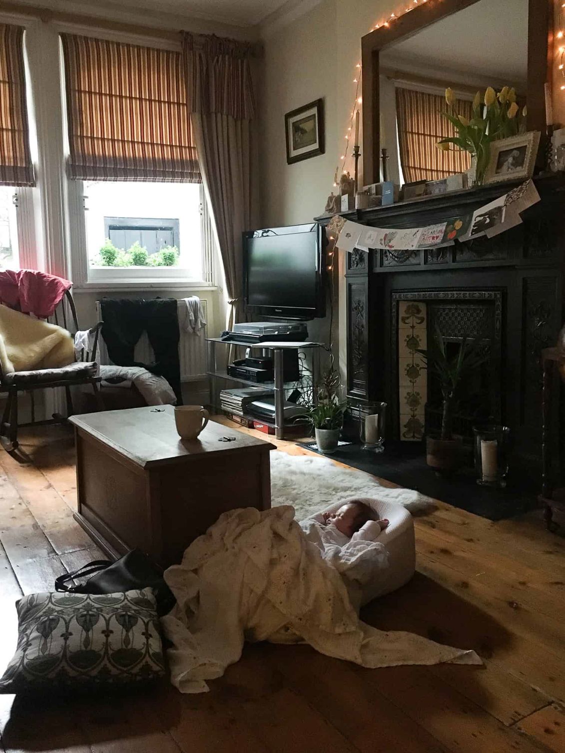 A baby sleeps in a London flat, the scene holds many details of everyday life.