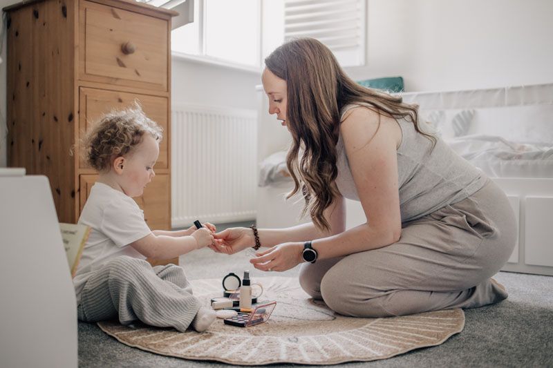 A little girl puts make-up on her Mum at home in Marlow at a motherhood photo session.