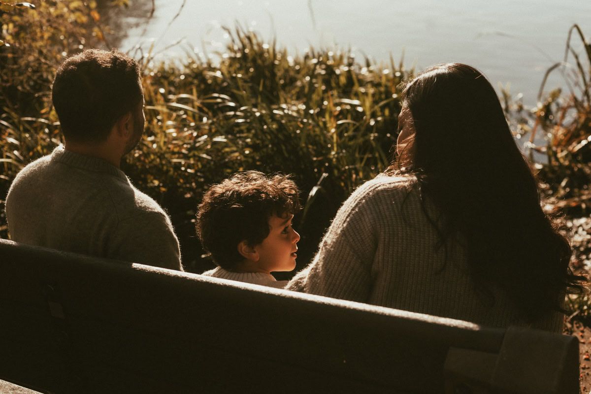 A family of three sit on a bench overlooking the river near Marlow Lock.  Taken by Emma Challinor, a local photographer.
