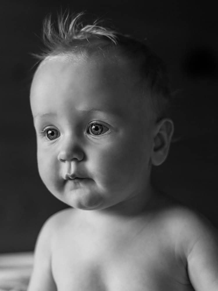 A 7 month old baby looks very expressive in this black and white portrait.