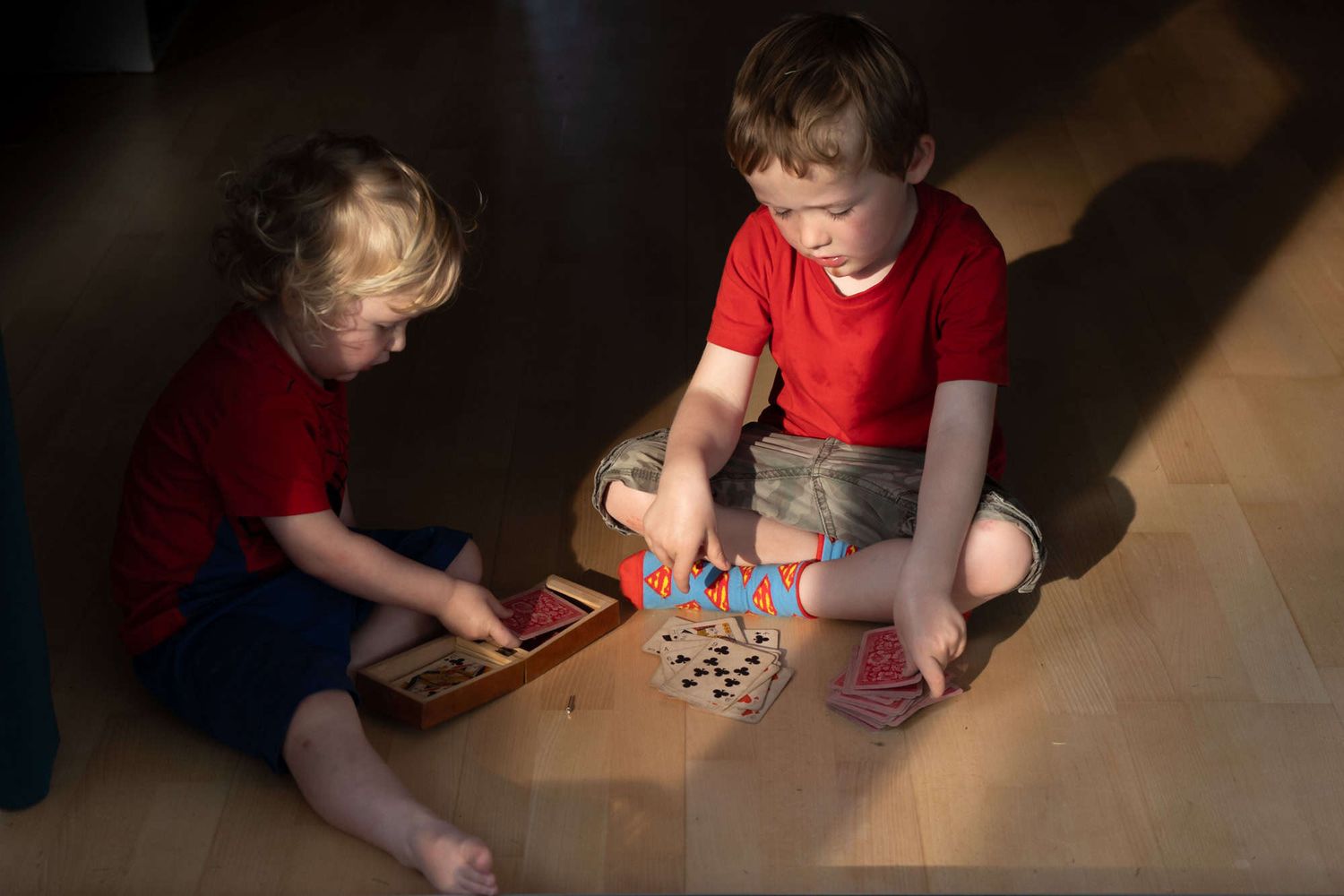 Two children sit playing cards together.