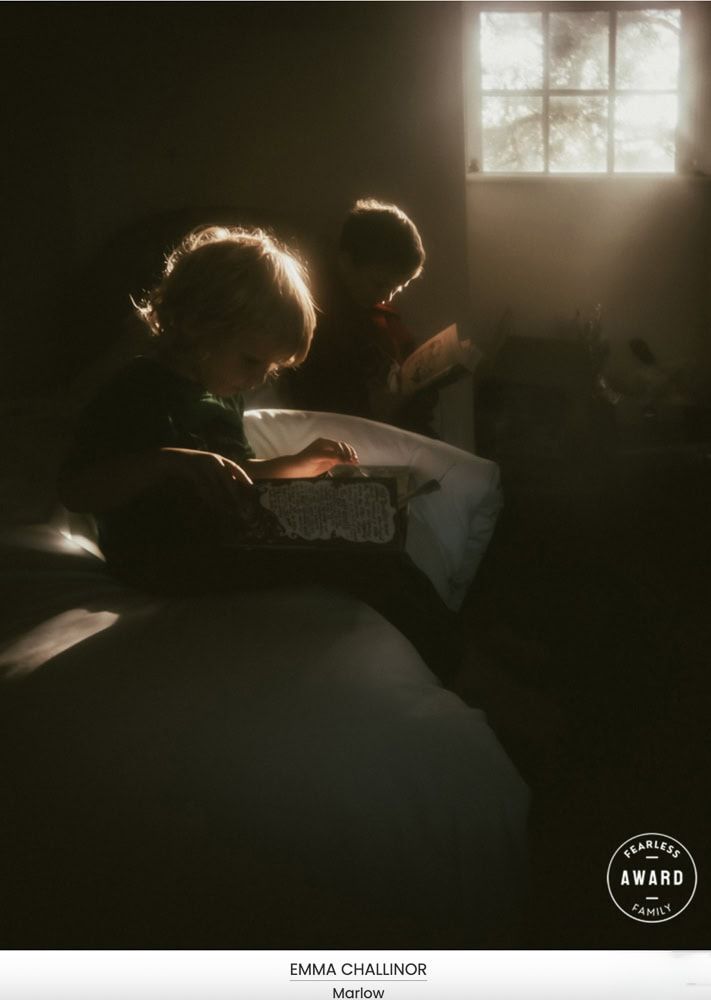 Two boys read together on a bed in beautiful light.