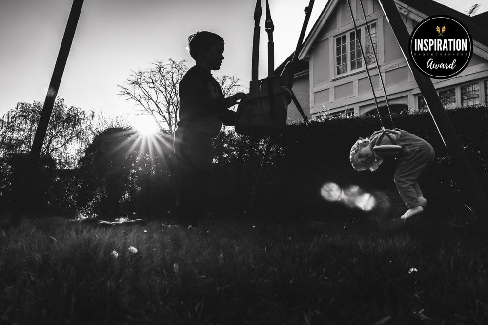 Two children play on a swingset towards sunset.