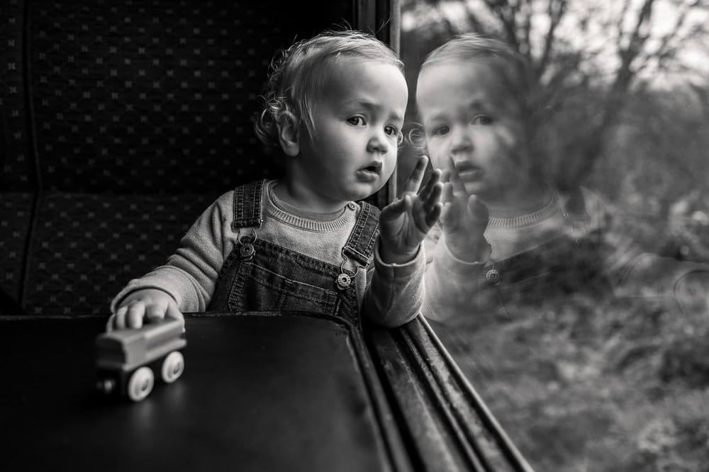 A young boys looks out of the window of a steam train with rapt attention.